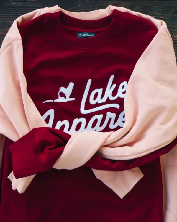 Lake Apparel organic crewneck sweatshirt with wool logo patch laid flat on wooden surface